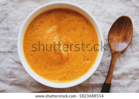 Hot pumpkin soup in a bowl on white background, top view, flat lay. Homemade autumn food. Popular Thanksgiving dish.