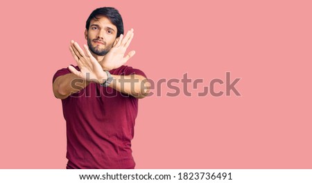 Handsome hispanic man wearing casual clothes rejection expression crossing arms doing negative sign, angry face 