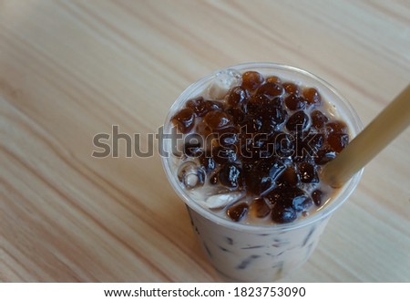 Konjac on top of Milk Tea Brown Sugar in  plastic cup with a large brown straw.