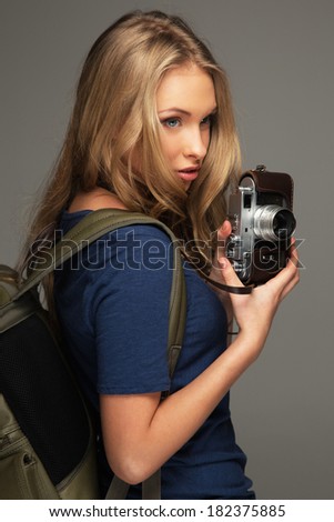 Positive young woman with long hair and blue eyes holding vintage style camera