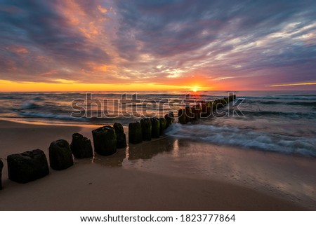 beautiful sunset on the Baltic Sea, waves washing the old wooden breakwaters