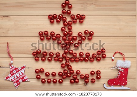 Christmas card. Christmas tree made of red beads on a light wooden background, and on the sides of the red and white heart and star. Flat bed, top view, copy space. Christmas frame, new year's banner 