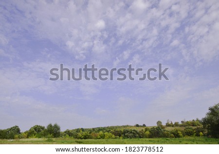 White feather clouds. Wildlife. Forest on the horizon. Village. Photo of the sky. Gloomy evening weather.