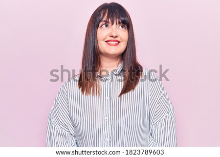 Young plus size woman wearing casual clothes looking away to side with smile on face, natural expression. laughing confident. 