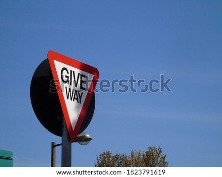 Low angle of  a give way sign under blu sky.