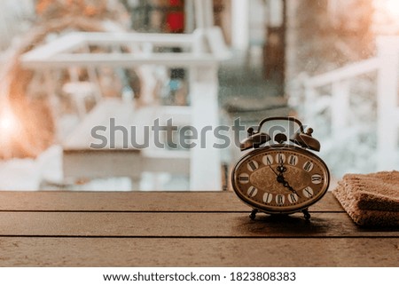 Clock on a table near the window ,vintage style.
