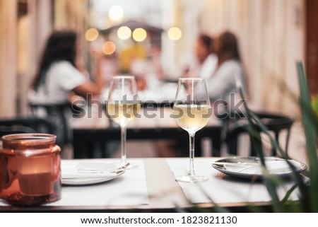 Two glasses of white wine on a table with candles, all set for a romantic dinner date, outdoor cafe