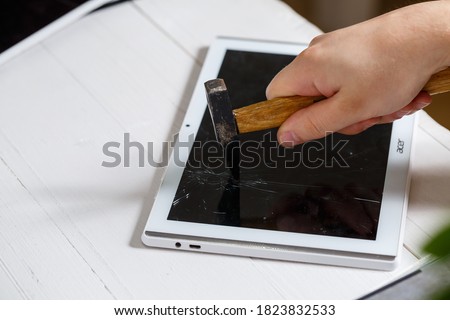 The hammer hits the broken touchscreen tablet, suggesting that it is about to replace it. Broken glass tablet repair