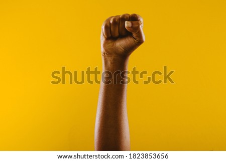 Black lives matter concept. white human arm painted in black on yellow colored background.