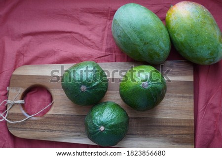 Green avocado and mango on a wooden chopping board against a green background. Healthy food. Style of life. Meals for vegans. Vegetable table
