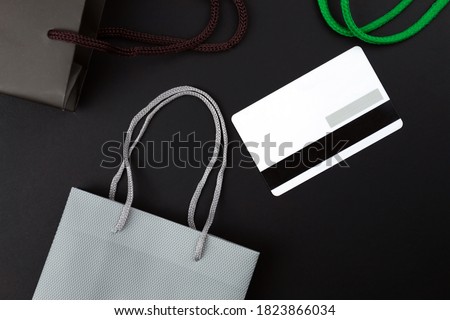 Gift bags and credit card on black background, black friday concept