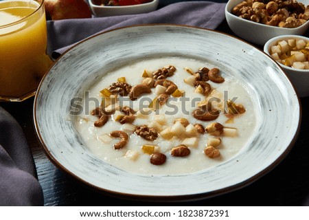photo of a Breakfast of rice porridge with pieces of nuts and dried fruit with orange juice on a gray background                               