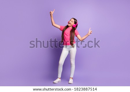 Full length body size photo of funky schoolgirl smiling listening to headphones singing favourite song isolated on purple color background