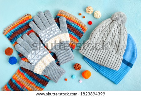 Hats, gloves and a scarf on a textured background. Warm clothes for autumn and winter in the form of hats, gloves and a scarf. Fashionable set of clothes made of hats and gloves.