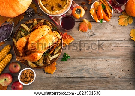 Thanksgiving dinner with chicken, cranberry sauce, pumpkin pie, wine, seasonal vegetables and fruits on wooden table, copy space. Traditional autumn holiday food concept.