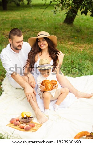 Picture of cheerful young caucasian female and male holds their child on hands, smiles and rejoices