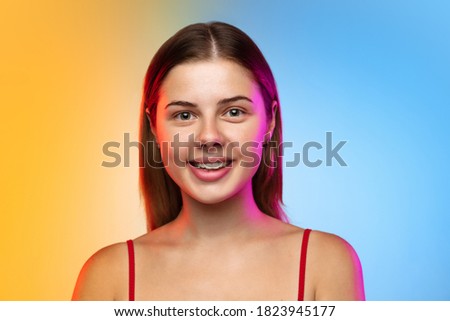 Caucasian young woman's portrait on gradient studio background in neon. Beautiful female model in casual style. Concept of human emotions, facial expression, youth, sales, ad.