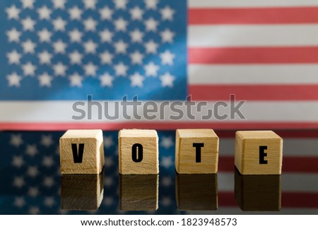 The word "vote" written on small wooden blocks against the background of the American flag became unfocused. The concept of the election campaign.