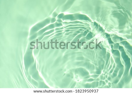 De-focused closeup of mint green transparent clear calm water surface texture with splashes and bubbles. Trendy abstract summer nature background. Mint colored waves in sunlight with copy space. Royalty-Free Stock Photo #1823950937