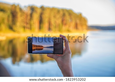 Woman hand holding smartphone taking photo picture of beautiful nature / mobile phone photography and video concept