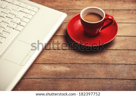 Cup of coffee and laptop on wooden table.