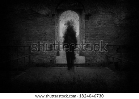 A spooky ghost, walking towards the camera, framed by the archway of an old building. With a grunge, vintage, blurred edit. Royalty-Free Stock Photo #1824046730