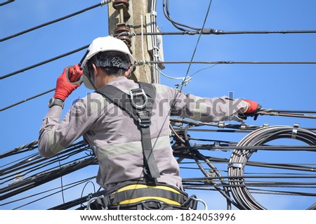 Electrical repair workers with walkie talkie on climbing poles