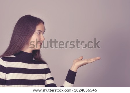 pretty teenager girl with hand gesture promotion sign standing isolated on gray background
