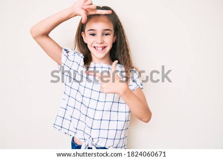 Cute hispanic child girl wearing casual clothes smiling making frame with hands and fingers with happy face. creativity and photography concept. 