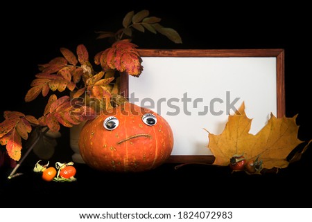 Portrait empty wooden frame mockup. Pumpkin with eyes, maple and rowan leaves. Black background. Thanksgiving, Halloween concept.