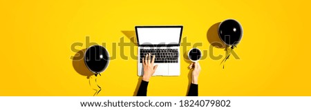 Person using a laptop computer with black balloons and coffee