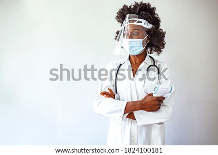 Coronavirus symptoms, woman in medical mask measures body temperature. Doctor looks at digital isometric non-contact thermometer in her hands, concept of cold and flu