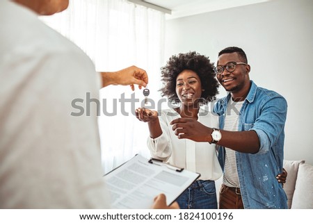 Photo of a smiling young couple thanking to the agent for the new house. Homeowners receiving their new house keys. Close up of a happy homeowners receiving their new house keys from a estate agent Royalty-Free Stock Photo #1824100196