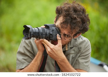 Photographer holdin a DSLR camera outdoors