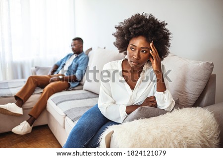 Shot of a young couple having relationship problems at home. Upset couple at home. Handsome man and beautiful young woman are having quarrel. Sitting on sofa together. Family problems.