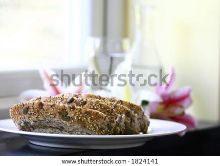 Four slices of malted bread with sunflower seeds and poppy, served on white plate , bottle and glass of water in the background