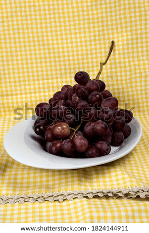 bunch of red organic grapes on a tray and tablecloth background