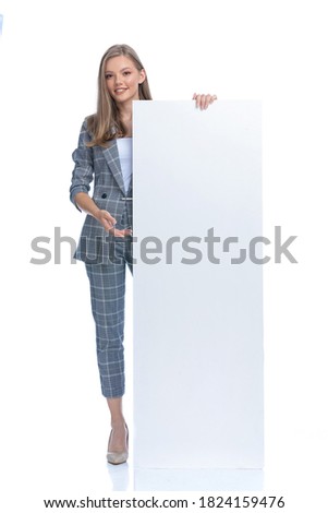 happy businesswoman in blue checkered suit holding and presenting empty board, smiling and standing isolated on white background, full body