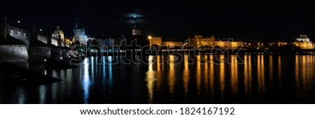 
panorama of Charles bridge and Vltava river and street lights at night in the center of Prague and reflections of lights on the surface of the Vltava river
