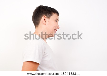 Profile of smiling boy with healthy skin, has contemplative expression, ready to have outdoor walk, isolated over white studio wall with copy space
