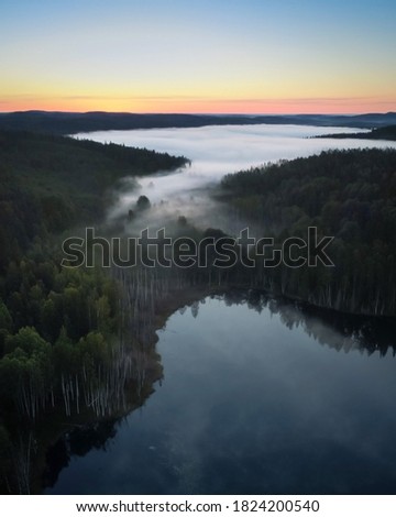 Morning fog over a mountainous area from a bird's eye view. Bright colors of dawn and misty river