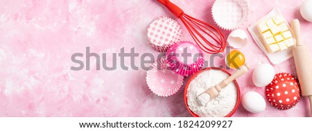 Baking background. Food ingredients for baking flour, eggs, sugar on pink background flat lay. Baking or cooking cakes or muffins. Long format with copy space. Top view Royalty-Free Stock Photo #1824209927