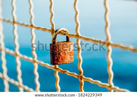 Rusty love padlock hanging on a bridge on a light blue sea background. Makarska, Croatia