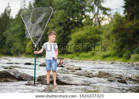 cute boy in white T shirt fishing in the river and has fun, smiles. vacation with kids, holidays, active weekends concept