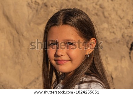 little girl child on the background of sands. Portrait of a girl. Young girl with long brunette natural hair in summer