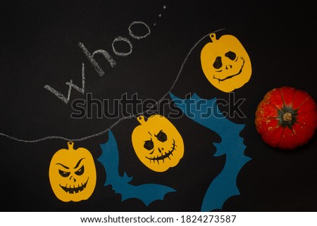 Halloween background with pumpkins and bats made of colored paper. On a black background, top view with the chalk inscription whoo