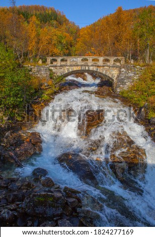 View of bridge over the waterfall in autumn. Waterfall in autumn colors. Northern Norway.Troms.