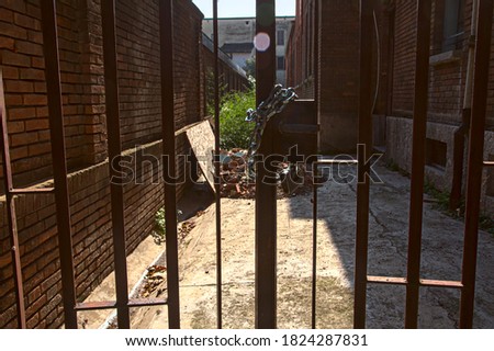 Backyard of an abandoned building closed by a chained gate