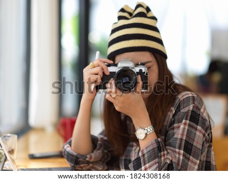 Portrait of female teenager taking photo with digital camera while relaxing in cafe 