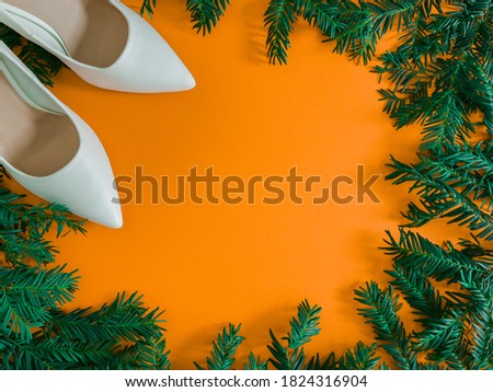 White shoes and christmas wreath.
White female shoes on the left and a Christmas wreath from a Christmas tree with a place for text in the middle, top view close-up.